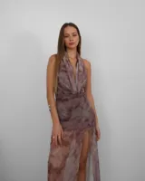 Vestido largo de microtul con estampado abstracto en tonos marrones y grises, con forro interno. Presenta escote drapeado y espalda descubierta.