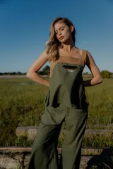 Conjunto de top y pantalón color beige. El top es de breteles anchos, con detalle en dos colores y un bordado en su delantera. El pantalón es liso, de corte recto ancho con bolsillos a los costados y cintura con botones y elástico.