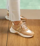 Zapatillas deportivas color beige con detalles dorados, cordones al tono y suela blanca.