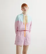 Mono corto deportivo con capucha, en bloques de color rosa y celeste, con cierre frontal naranja.