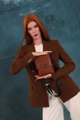 Bandolera tipo phone bag pequeña, color marrón claro, con correa de galón regulable. Tiene un compartimento principal y un bolsillo adicional con tapa.