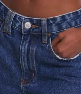Short de jean azul oscuro, de tiro alto, con bolsillos delanteros y traseros, cierre con botón y cremallera, trabillas dobles y terminación deshilachada.