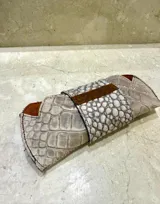 Estuche para lentes con textura símil cocodrilo en tonos beige y marrón.