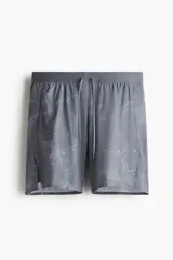 Short deportivo gris con estampado de mármol, con cintura elástica ajustable con cordón, bolsillos laterales con cierre y calza interior con bolsillo para celular.