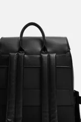 Mochila negra de cuero sintético con solapa y cierre magnético. Tiene un compartimento principal con espacio para dispositivos electrónicos de hasta 13 pulgadas y un bolsillo con cierre. En la parte frontal tiene un bolsillo con cierre y bolsillos planos en los laterales. La parte posterior es acolchada y tiene una banda de sujeción para equipaje. Tiene asa de mano y dos asas de hombro ajustables y acolchadas.