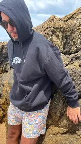 Hoodie negro de corte oversize con cordones ajustables y estampado frontal de una hoja blanca.