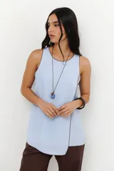 Musculosa color crudo con cuello redondo y ribete marrón en cuello, sisas y ruedo. Diseño cruzado en el frente y aberturas laterales.