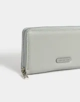 Billetera negra rectangular con cierre circundante y tag metálico con logo.