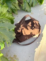 Bolso marrón de cuero con doble correa, interior forrado con bolsillos y llavero, cierre de lado a lado.