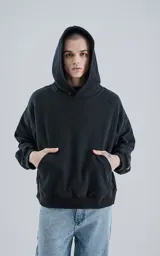 Hoodie negro de frisa gamuzada 100% algodón, de calce oversize crop, con bolsillo canguro y capucha forrada.