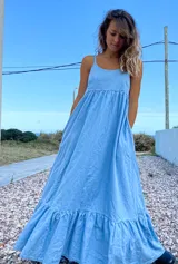 Maxi vestido celeste de jean con breteles regulables y bolsillos laterales.