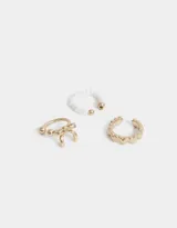 Set de tres earcuffs dorados, uno con perlas blancas, otro con un moño y otro con corazones.