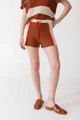 Short tejido en jersey color marrón con detalles de rayas verticales en color crema y ribete naranja.