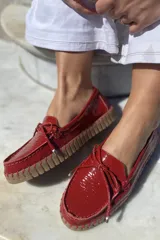 Mocasín náutico dorado de cuero con detalle de lazo en la parte delantera y suela de goma color caramelo.