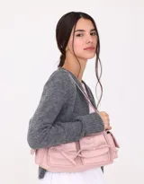 Bandolera rosa claro de cuerina con manija superior y cierre principal. Presenta doble bolsillo frontal y bolsillos laterales, todos con broche lazo con botón para cerrado.