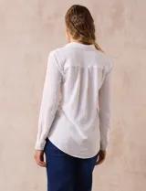 Camisa blanca de manga larga con cuello con solapa y abertura central con botones. Tiene dos bolsillos delanteros aplicados.