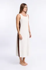 Vestido largo sin mangas, color crudo, con textura de tejido de punto abierto y escote cuadrado. Presenta paneles laterales en color marrón oscuro.