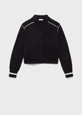 Chaqueta bomber de punto color negro con cierre de botones a presión, cuello redondo y bolsillos ribeteados. Presenta ribetes blancos en contraste en hombros y puños.