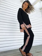 Conjunto de buzo y pantalón negro con detalles en color beige. El buzo es de corte holgado, con cuello en V y puños con ribete. El pantalón es de corte recto y tiro alto.