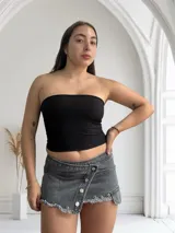 Pollera mini de tiro bajo, con detalles de botón y terminaciones desflejadas.