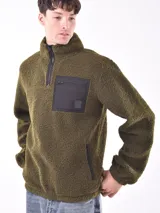 Buzo de polar verde oliva con cierre de medio largo y bolsillo de nylon negro en el pecho.