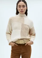 Sweater de punto grueso color beige con diseño patchwork. Tiene cuello alto y mangas largas.