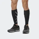 Mangas de compresión para pantorrilla (calf guards) color negro, con diseño de líneas curvas blancas en el frente y logo 2XU en blanco en la parte trasera.