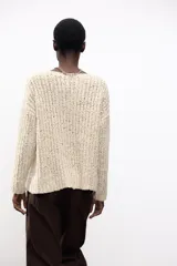 Sweater color crema de tejido de punto grueso, con cuello redondo amplio y mangas largas.