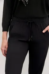 Pantalón babucha negro de calce relajado, con elástico y cordón ajustable en la cintura, bolsillos diagonales en el frente y falsos bolsillos ojal en la espalda.
