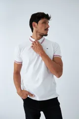 Remera cuello polo blanca de piqué, corte regular, manga corta, logo estampado y terminaciones a contratono en cuello y mangas con rayas rojas, grises y azules.