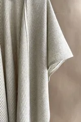 Ruana marrón con diseño a cuadros blancos, terminación envivada y flecos cortos.