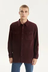 Camisa de corduroy color marrón, con corte recto, bolsillos frontales y cierre de botones.