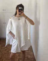 Capa/Poncho de tejido de punto calado color blanco hueso, con cuello redondo y caída amplia.