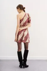 Vestido corto de un hombro, con manga larga con frunces en el hombro y ajuste con elástico en la cintura. Confeccionado en viscosa jacquard con lurex, con estampado de manchas color dorado sobre fondo borgoña.