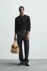 Jersey negro de lana con acabado mercerizado, corte relaxed fit, cuello redondo y mangas largas con terminaciones en rib.
