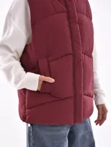 Chaleco puffer color bordó con capucha y bolsillos laterales.