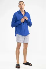 Short de baño blanco con estampado de lunares azules y naranjas. Cuenta con cintura elástica con cordón regulable, bolsillos laterales y bolsillo trasero con cierre.