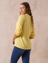 Blusa blanca de poliéster y rayón con escote en V bordado y mangas tres cuartos regulables con presilla y botón.