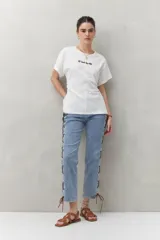 Remera blanca de manga corta con bordado frontal "C’est la vie", calce relajado y frunces laterales.