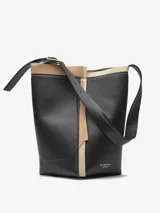 Bolso tipo tote de cuero negro con detalles en beige y correa larga ajustable con hebilla metálica.
