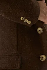 Blazer marrón de lana con solapas de muesca, cierre con dos botones dorados, bolsillos con solapa y forro interior a tono.