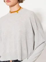 Sweater tejido suave y flojo, color crudo, con cuello redondo y mangas largas.