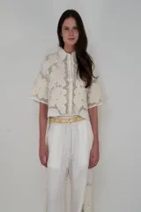 Camisa blanca de lino con cuello solapa y apliques de flores en el frente y mangas. Corte crop.