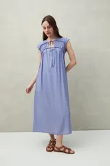 Vestido largo lila con escote con lazo, mangas cortas y frunces en el pecho.