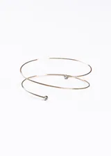 Brazalete dorado de metal con diseño entrelazado y dos puntos de luz.