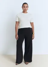 Remera de punto fino color blanco, de manga corta y cuello redondo, corte entallado.