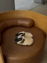 Zueco blanco de peluche con hebilla decorativa, diseño cómodo y moderno.