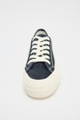 Zapatillas bajas de denim azul oscuro con cordones blancos y suela de plataforma color crema.