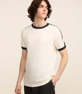 Remera blanca de algodón con cuello redondo, manga corta y rayas azules en los hombros.