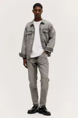 Pantalón de jean gris con efecto lavado, corte regular tapered, tiro medio, cinco bolsillos y cierre con botón y cremallera.